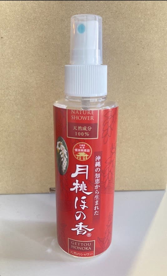 베이지색 배경에 "Nature Shower"라는 단어가 적힌 빨간색 스프레이 병. 흰색 스프레이 노즐 및 캡.