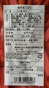 「軽井沢のお土産人気商品 国産梅肉ごぼう 250g 5袋セット」の日本語ラベルのクローズアップ写真には、原材料や栄養成分表示、保存方法、製造元情報が日本語で記載されており、下部にはバーコードが印刷されています。 パッケージからは、中に入っている赤い「国産梅肉ごぼう」が見えます。この人気セットは、軽井沢のお土産としてトップクラスの売れ行きを誇っています。.